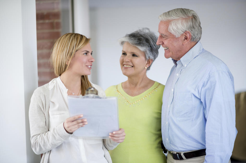 Woman consulting with senior couple, discussing care options, emphasizing hospitality in senior living services.