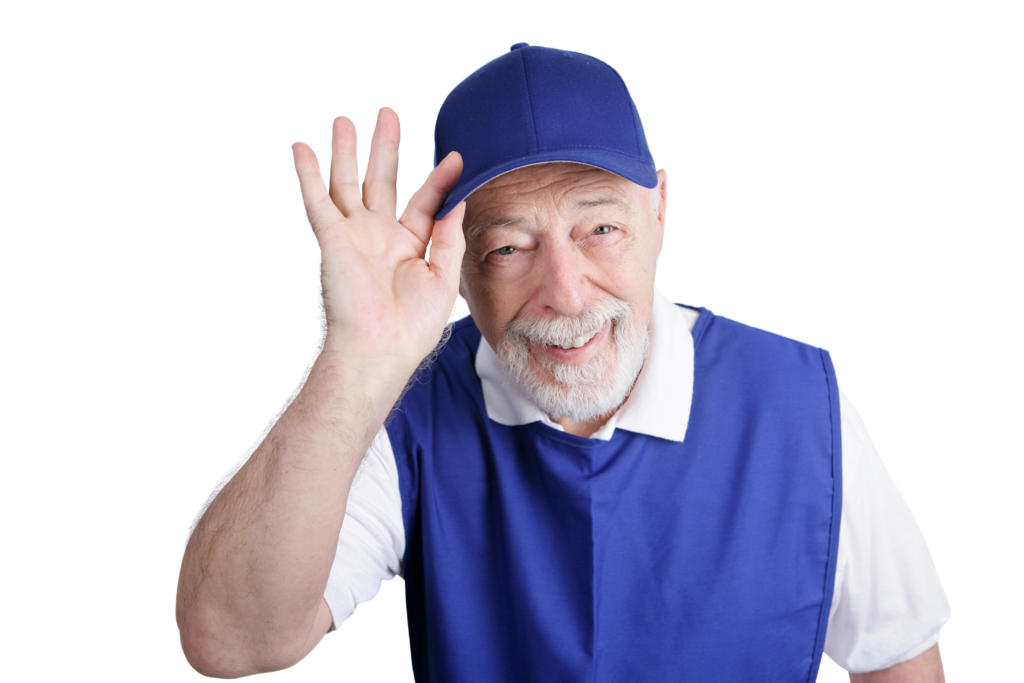 Smiling elderly man in blue uniform and cap, waving, representing high-level service and hospitality in senior living.